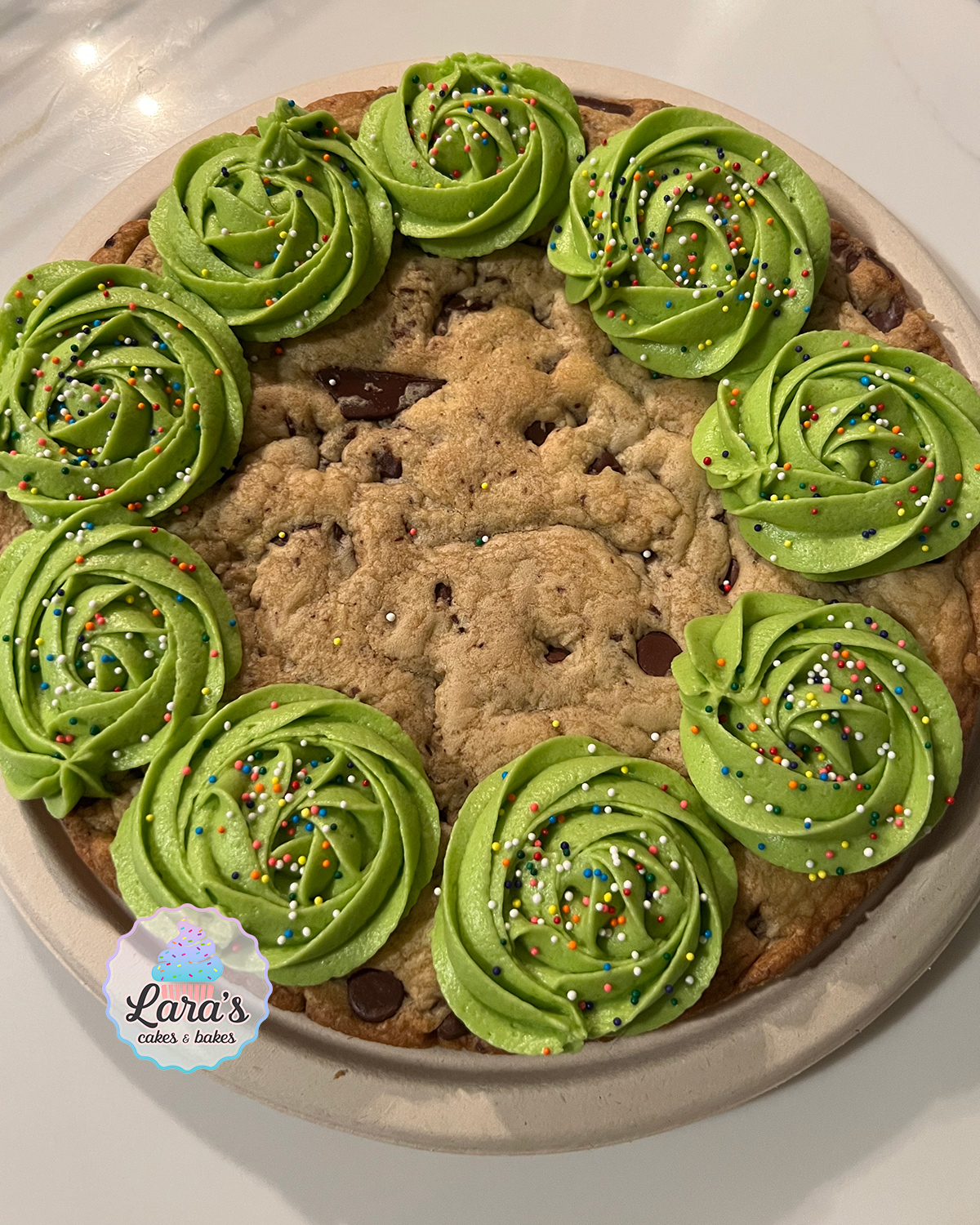 Chocolate chip cookie cake with green buttercream icing and rainbow sprinkles