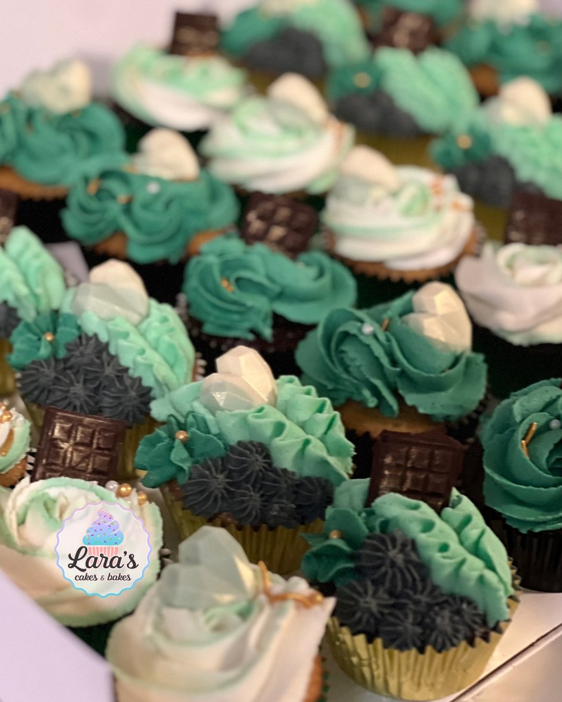 Cupcakes with green, white, and dark grey buttercream designs and candy toppers.